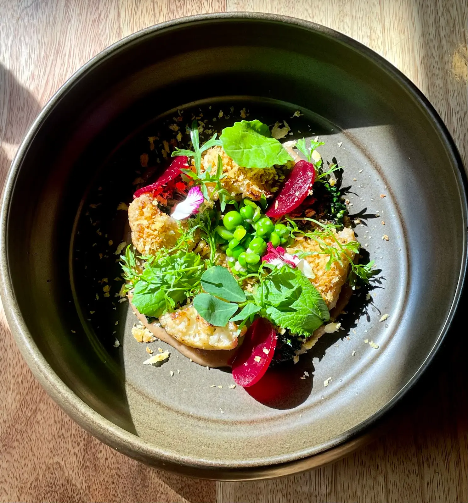 Tasting course of greens, peas and pickled beetroot served in a hand-thrown bowl