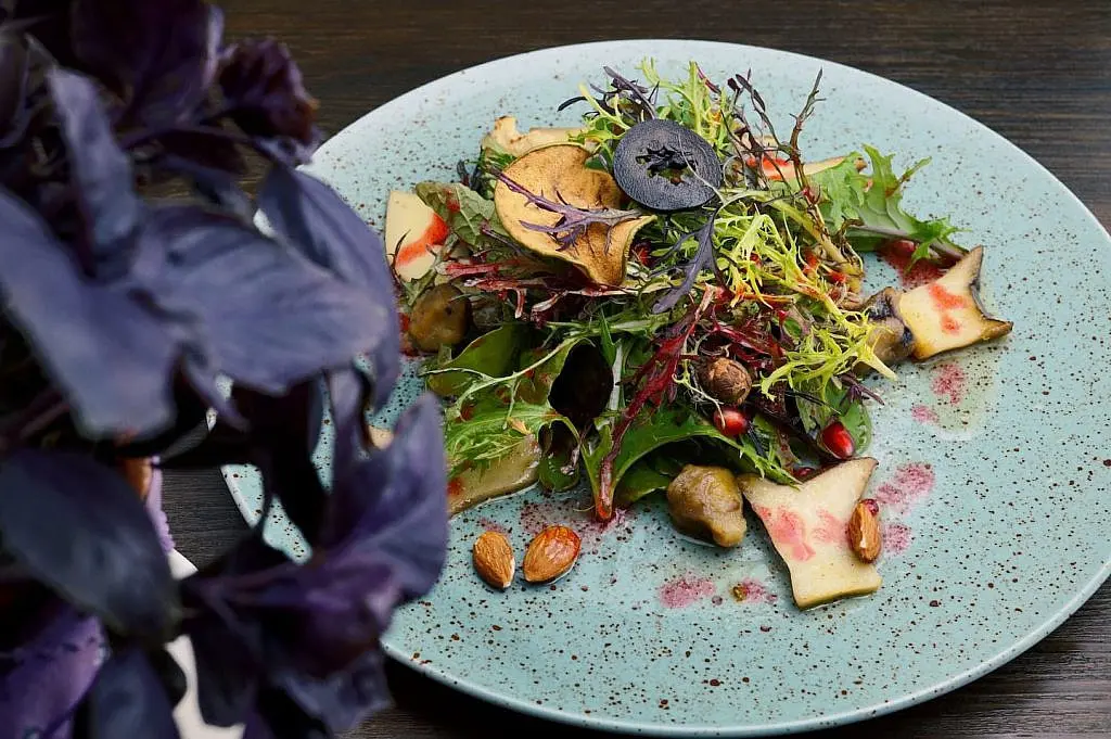 Foraged greens salad with purple basil on a speckled blue ceramic plate